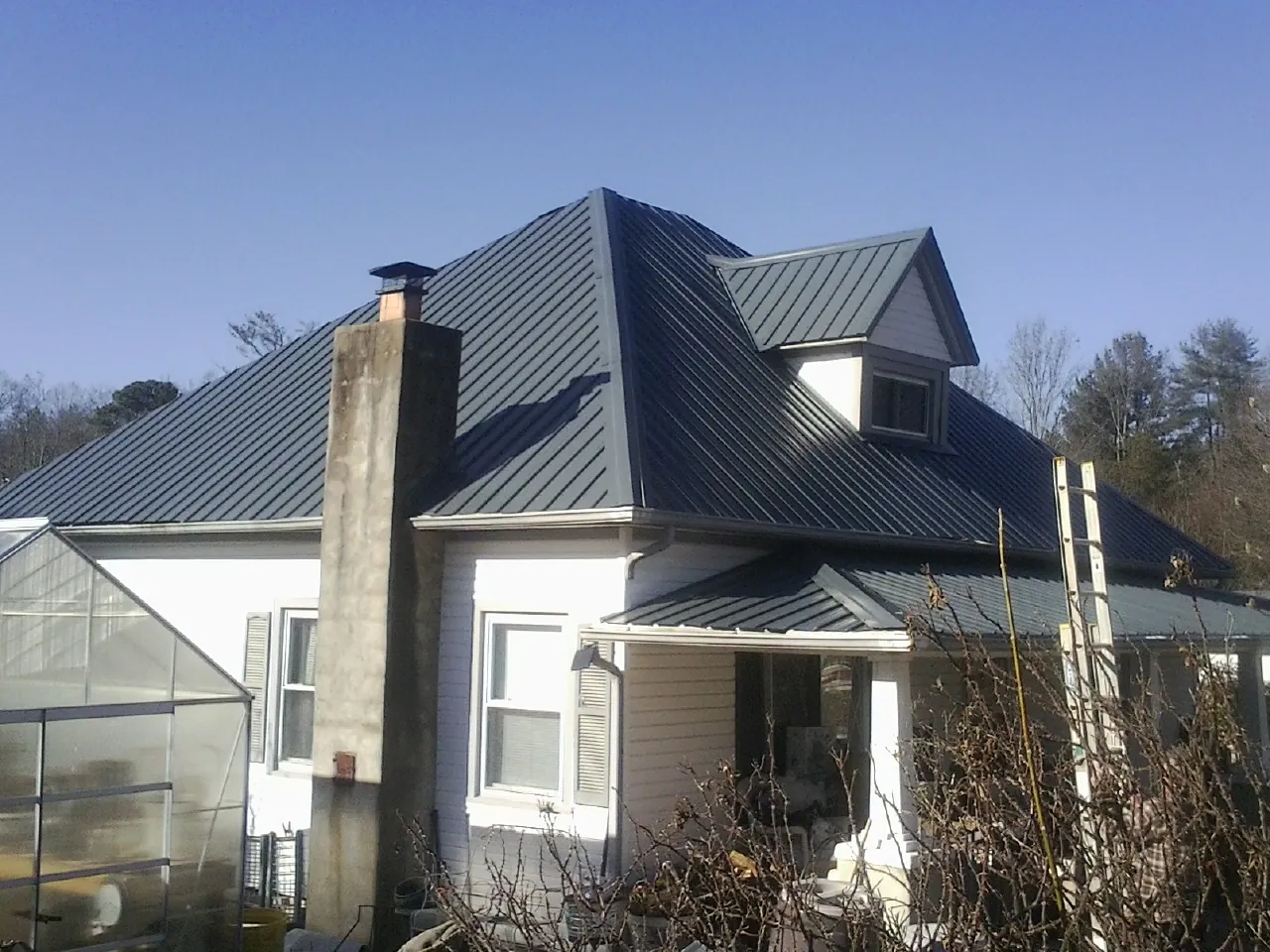 Dark blue standing seam metal roof on a white farmhouse with dormer — Slate & Tile Roof Repair by Roofing Brothers in Nevada City