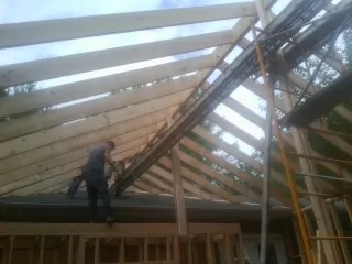 Rafters going up over a new addition with a worker on the wall in Nevada City
