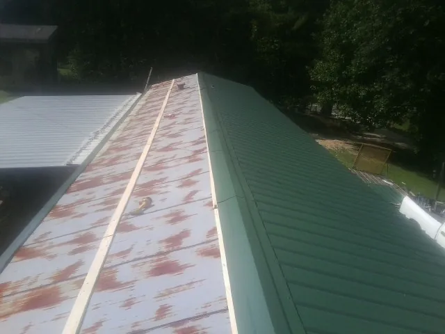 Old rusted panels beside newly installed green metal roofing — Wind Damage Roof Repair by Roofing Brothers in Nevada City