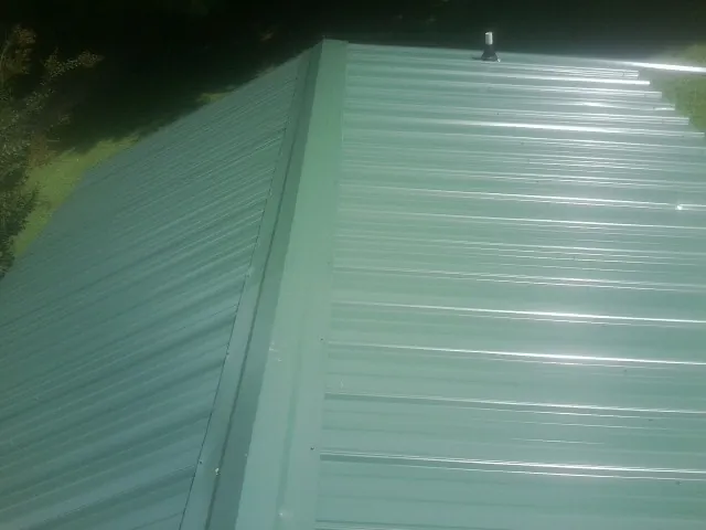 New green metal panels meeting at the ridge of a roof — Flat Roof Repair work by our crew in Nevada City