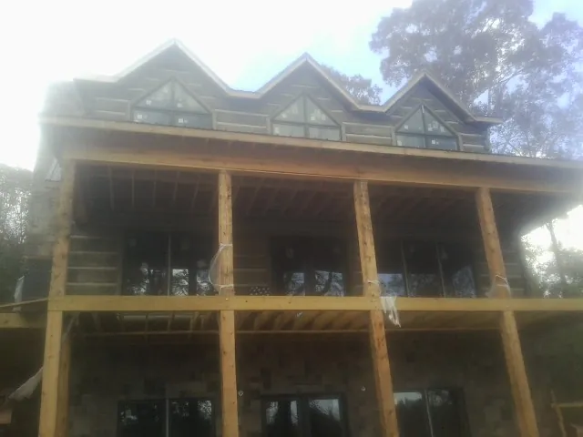 Dormers and porch framing on a large log home under construction — Roof Coating work by our crew in Nevada City