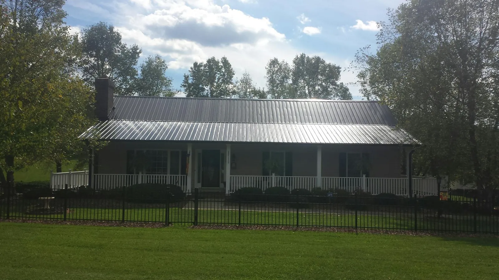 Gray metal roof on a brick ranch with a full width front porch — Gutter Guard Installation work by our crew in Nevada City