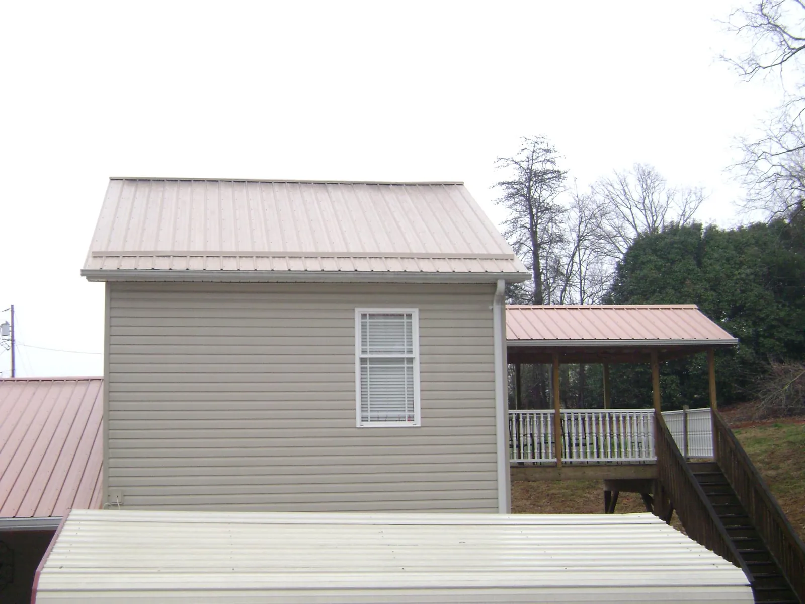 Tan metal roofs on a two story addition and attached porch, from a Roof Replacement job in Nevada City