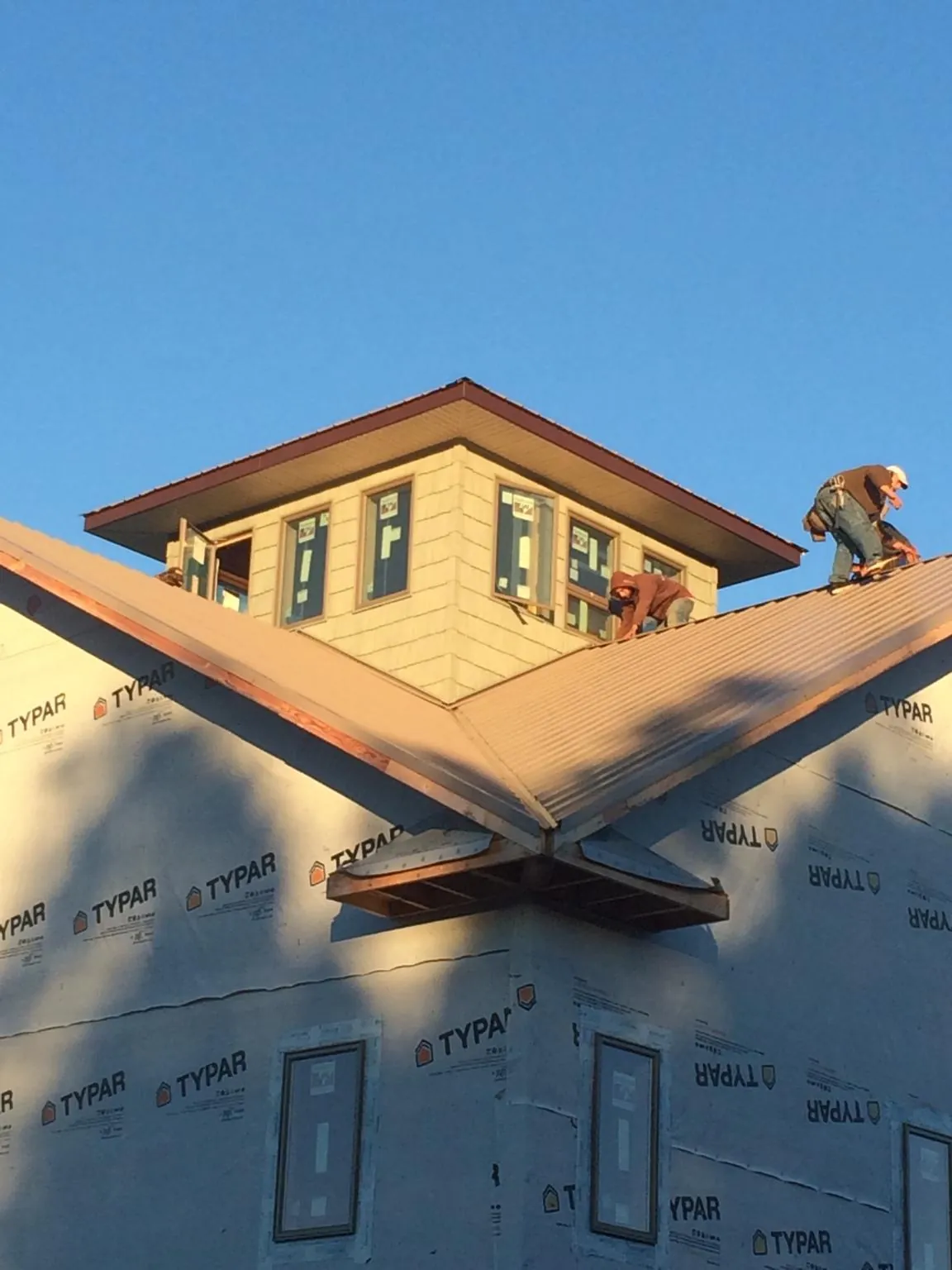Roofers working around a rooftop cupola on a new metal roof at sunset — Roof Waterproofing in Nevada City by Roofing Brothers